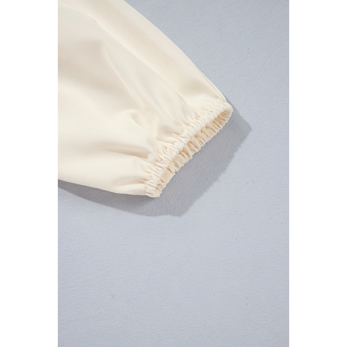 Blusa avorio arricciata con maniche a palloncino — dettaglio del polsino