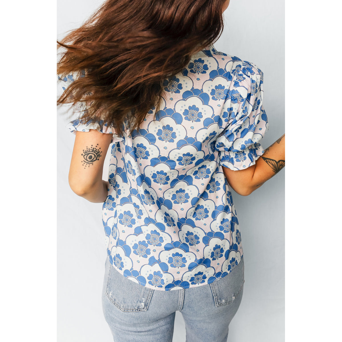 Blusa azzurra floreale con scollo a V e bordi a contrasto — vestibilità sul retro