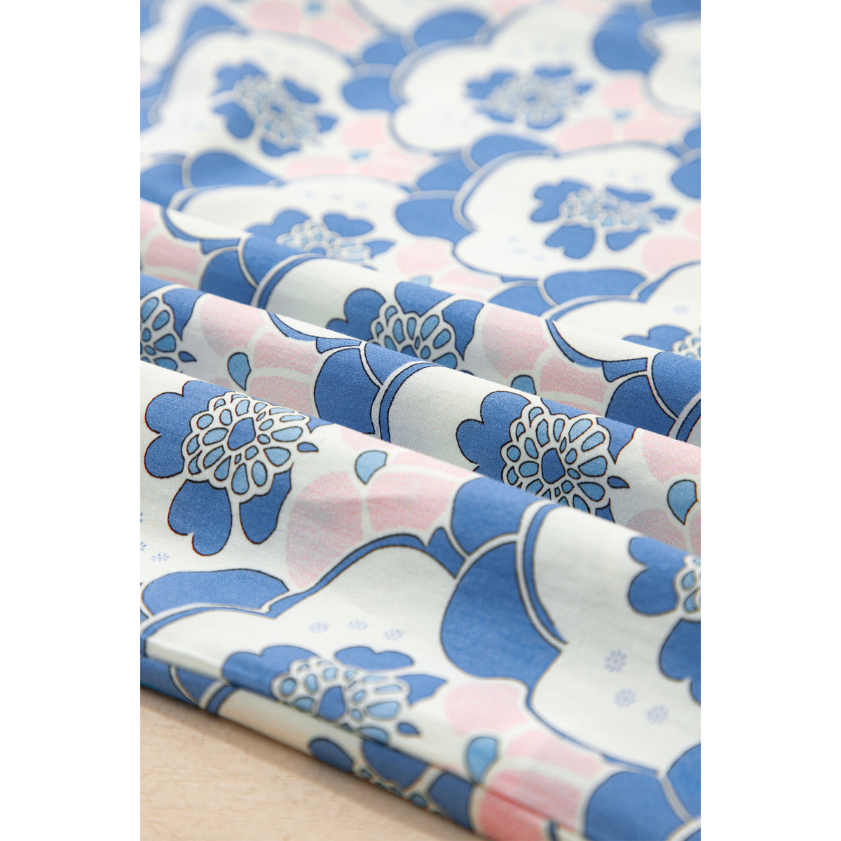 Blusa azzurra floreale con scollo a V e bordi a contrasto — dettaglio del tessuto floreale