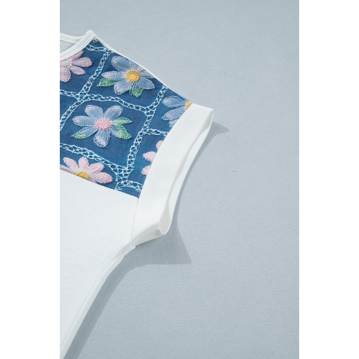 Blusa bianca a maniche corte con inserti floreali — dettaglio dell’inserto sulla manica