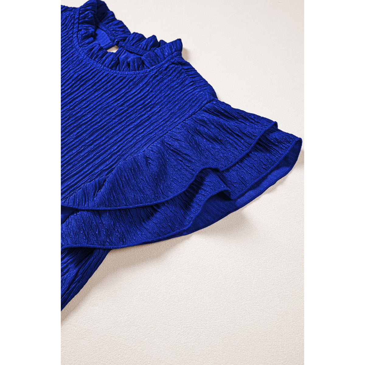 Blusa blu scuro in tessuto lavorato con maniche a volant — dettaglio della manica a volant