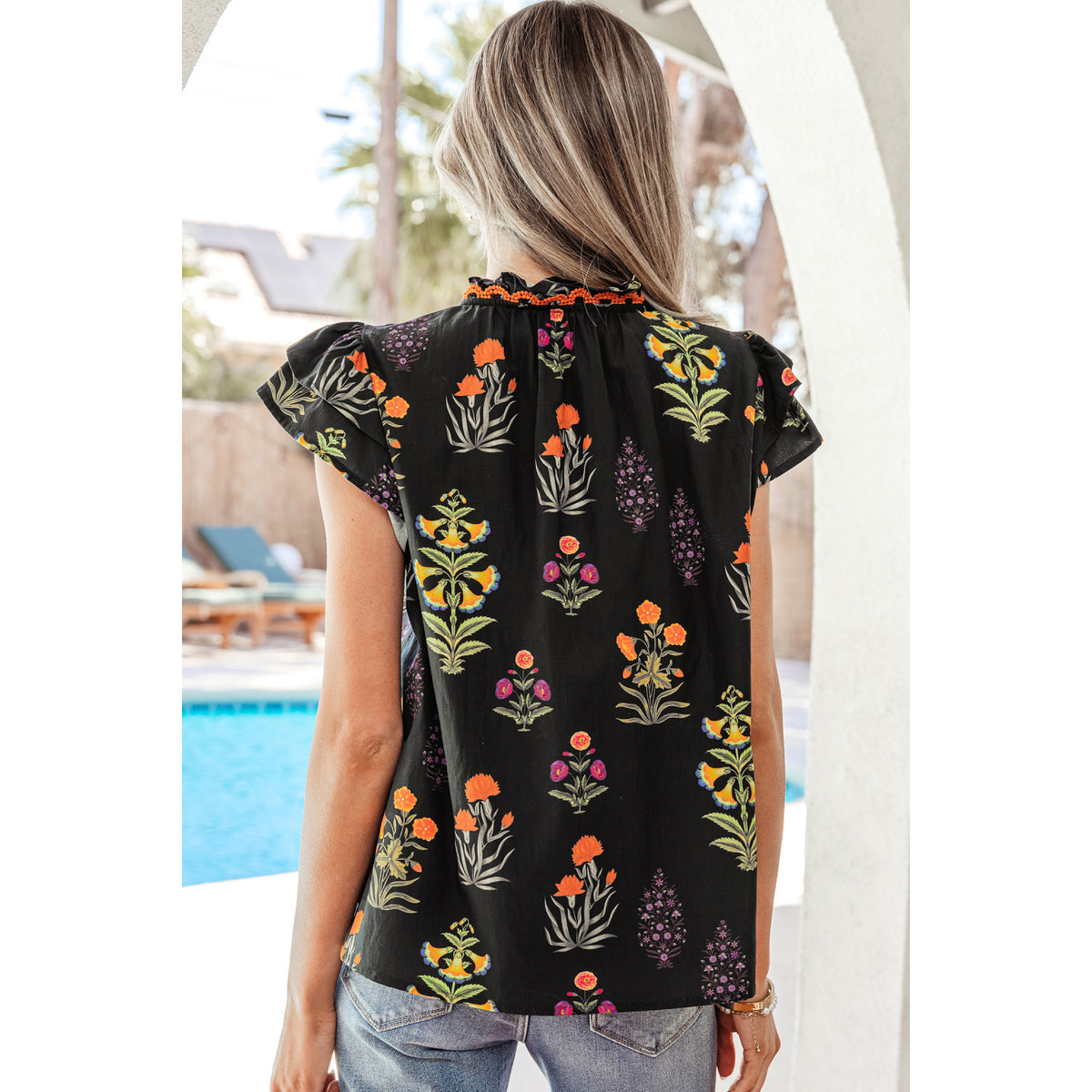 Camicia nera floreale con scollo a V e volant — vestibilità sul retro