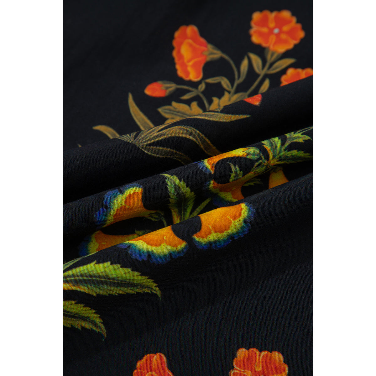 Camicia nera floreale con scollo a V e volant — dettaglio del tessuto floreale
