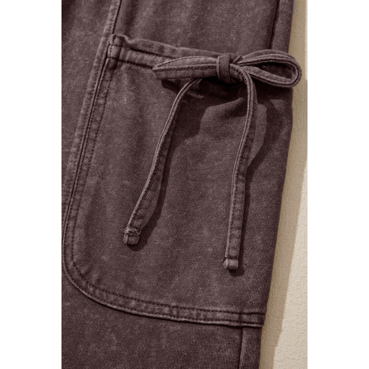 Pantaloni cargo marrone scuro in cotone con lavaggio minerale — dettaglio del laccio sulla tasca cargo